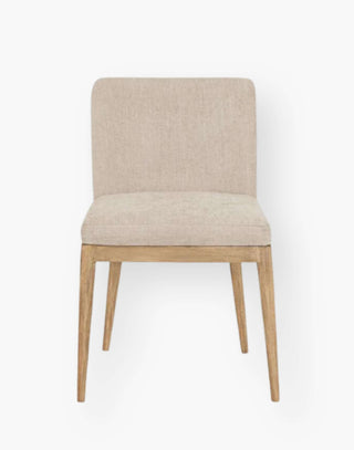 Dining chair with light wooden legs and cream colored upholstery.