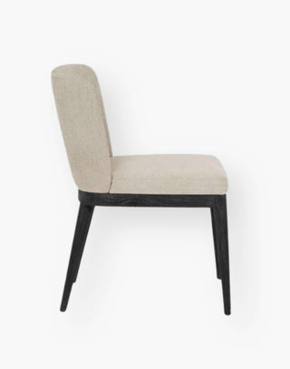Dining chair with black wooden legs and cream colored upholstery.