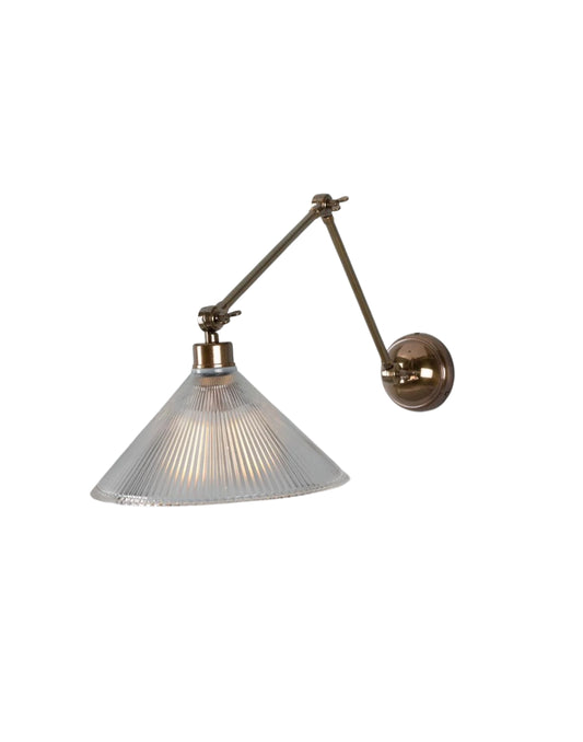 Adjustable brass wall sconce with articulated arm and ribbed prismatic glass shade for focused task lighting.