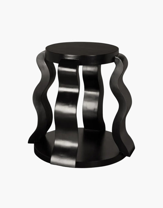 Round black side table with sculptural ribbon legs and open shelf in hand-rubbed black finish.