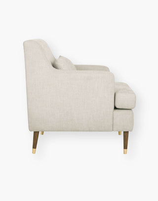 Tailored chair with recessed arms and a slightly reclined back with brass capped legs.