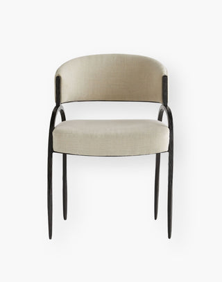 Dining chair with a linen upholstered curved back and large seat rest on a iron frame with natural iron details along a thin frame.