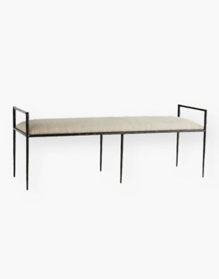 Iron body bench perched on a sharp angled frame with an upholstered seat in natural linen.