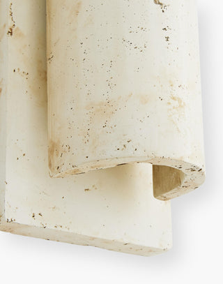 Sconce made of a cast stone composite in a light-washed terracotta finish.