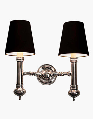 Elegant Carlton Twin Wall Sconce in cast brass with classic period design, featuring two light fixtures with ivory or black lampshades for balanced, warm illumination in vintage-inspired decor.