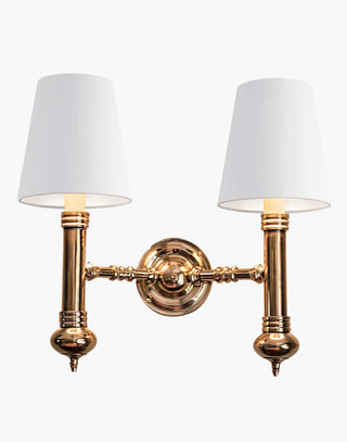 Elegant Carlton Twin Wall Sconce in cast brass with classic period design, featuring two light fixtures with ivory or black lampshades for balanced, warm illumination in vintage-inspired decor.