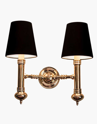 Elegant Carlton Twin Wall Sconce in cast brass with classic period design, featuring two light fixtures with ivory or black lampshades for balanced, warm illumination in vintage-inspired decor.