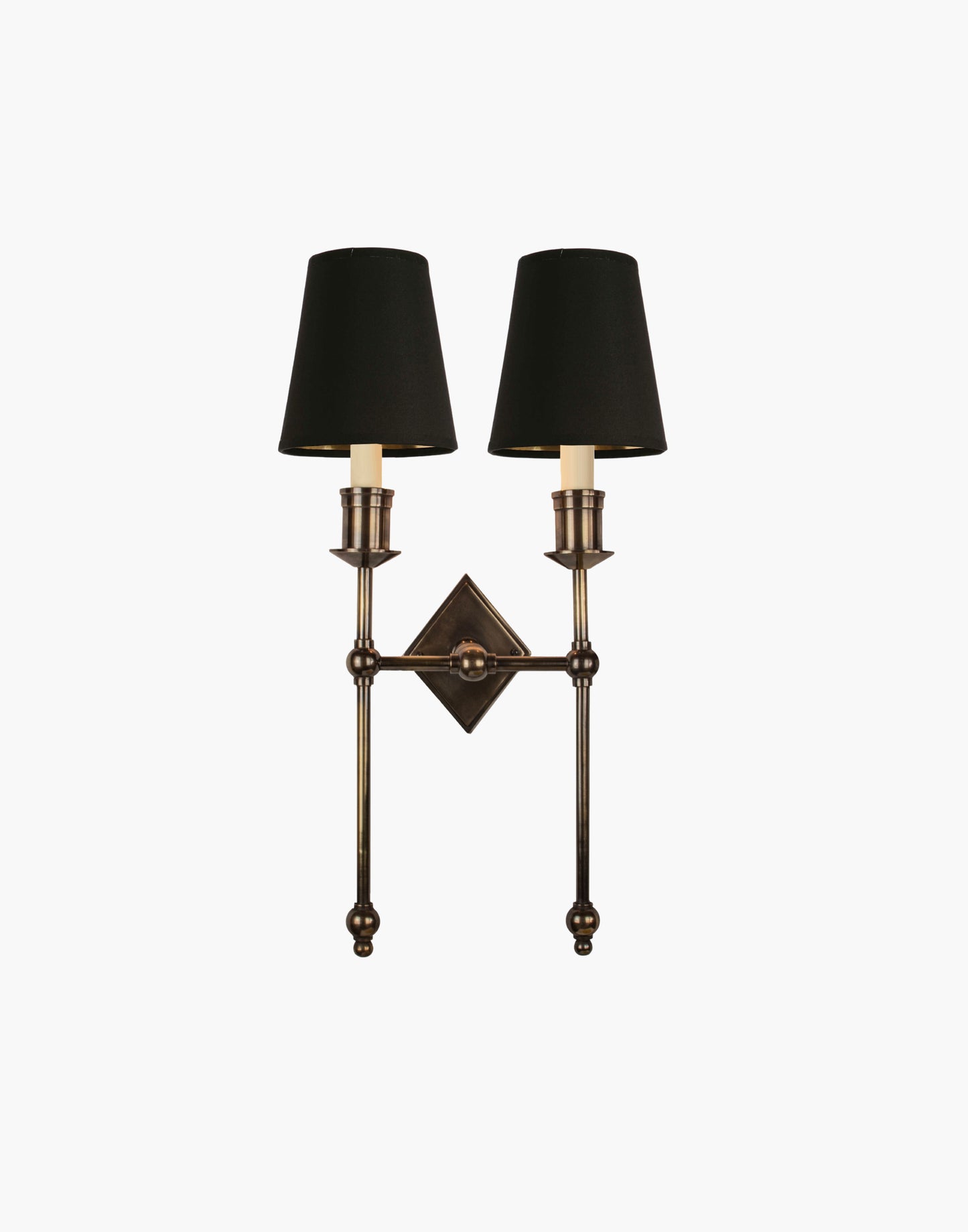 Wall sconce in cast and machined brass with diamond-shaped scalloped backplate and twin candle arms.
