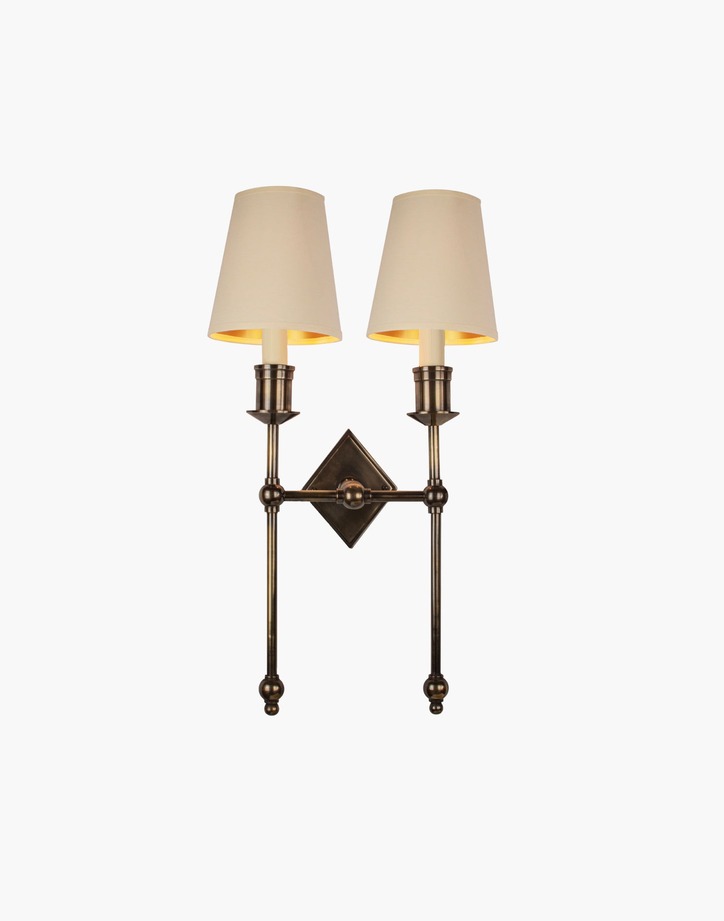Wall sconce in cast and machined brass with diamond-shaped scalloped backplate and twin candle arms.