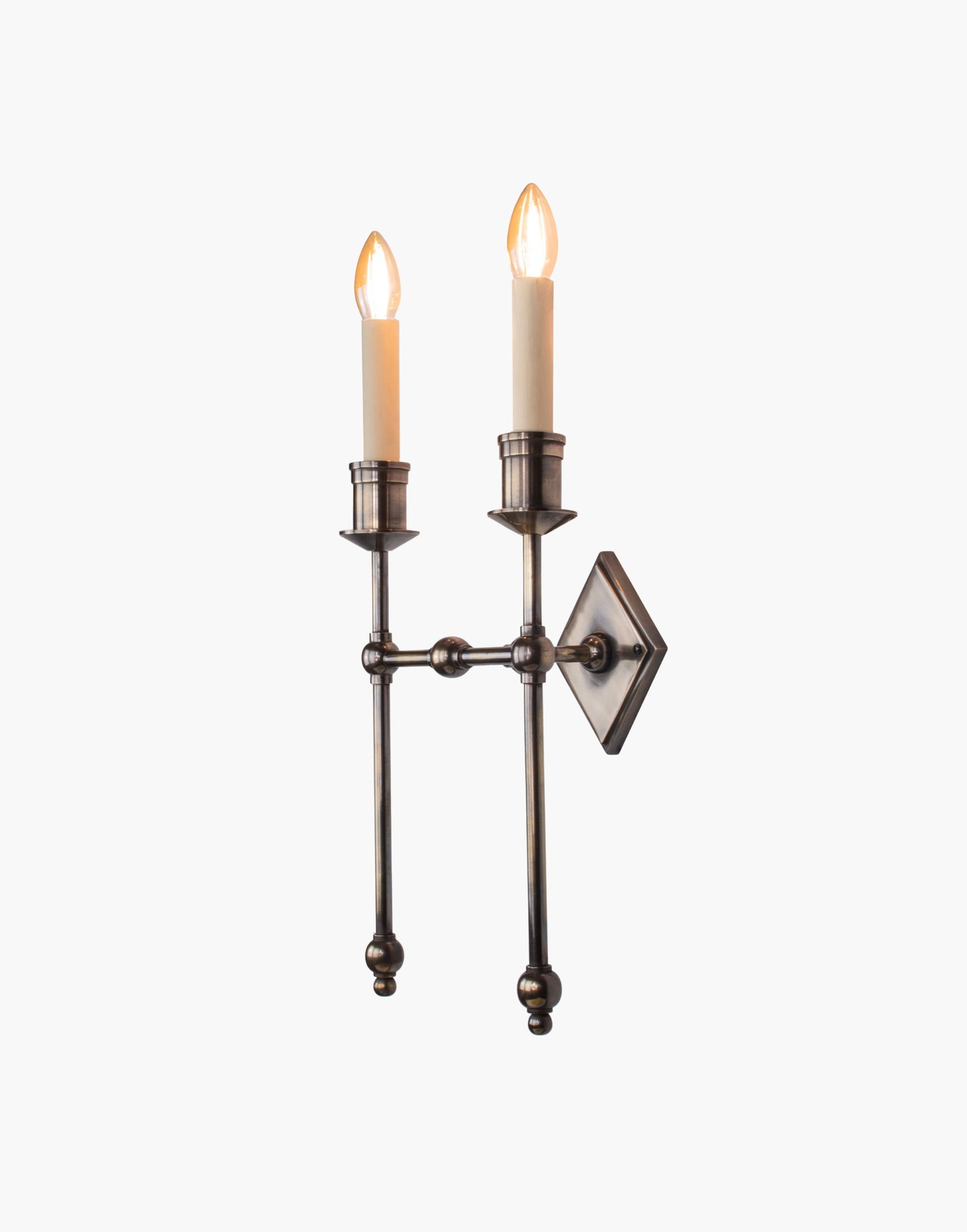 Wall sconce in cast and machined brass with diamond-shaped scalloped backplate and twin candle arms.