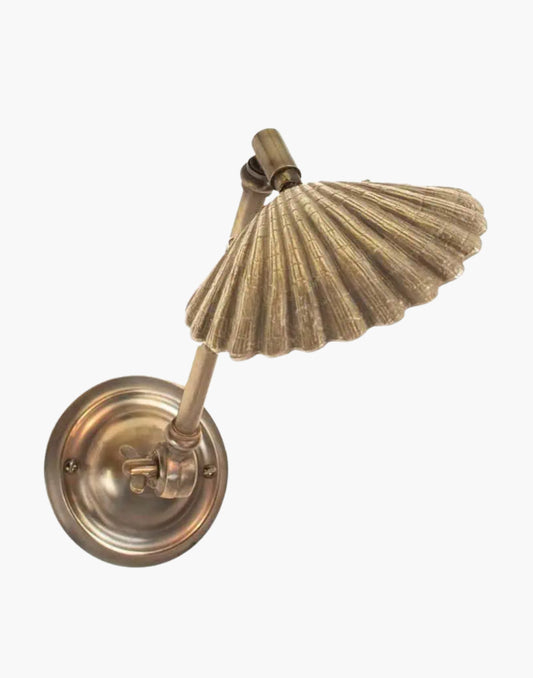 adjustable brass wall light with sculptural cast shade and articulated arm, designed as an elegant bedside or reading wall sconce.