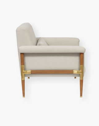 Chair with brass elbows on a wood frame with textured, natural-hued performance fabric.