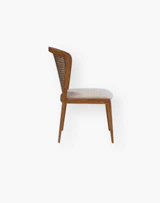 Dining chair with woven natural materials, a wood frame, curved cane back, and the seat cushion is finished in a performance fabric.