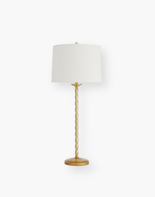 Table lamp with stacked, slender polished brass bubbles on a brass base topped with an off-white linen drum shade with off-white cotton lining.