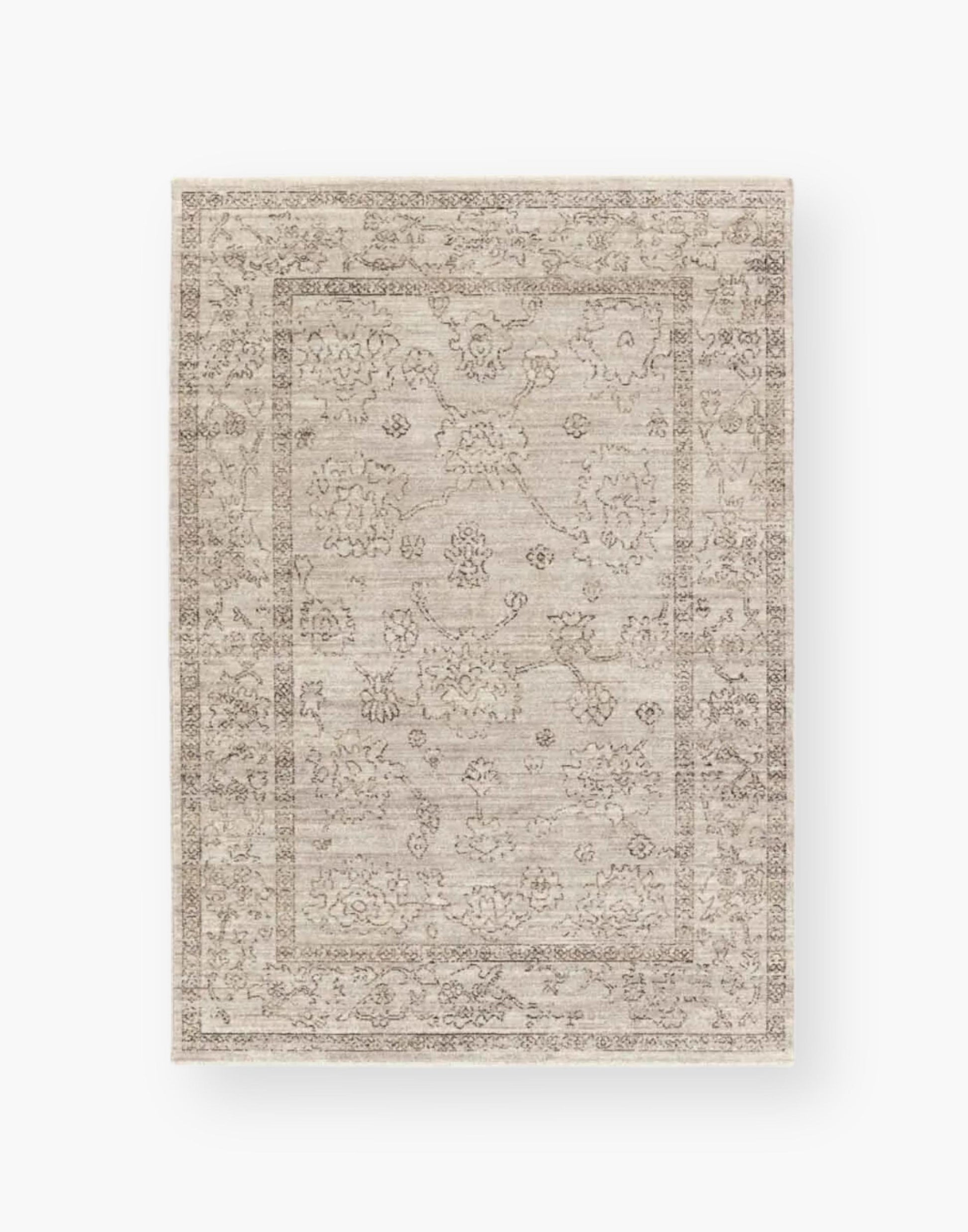 Polyester area rug that features a distressed, floral design in warm tones of brown, gray, taupe, and cream.