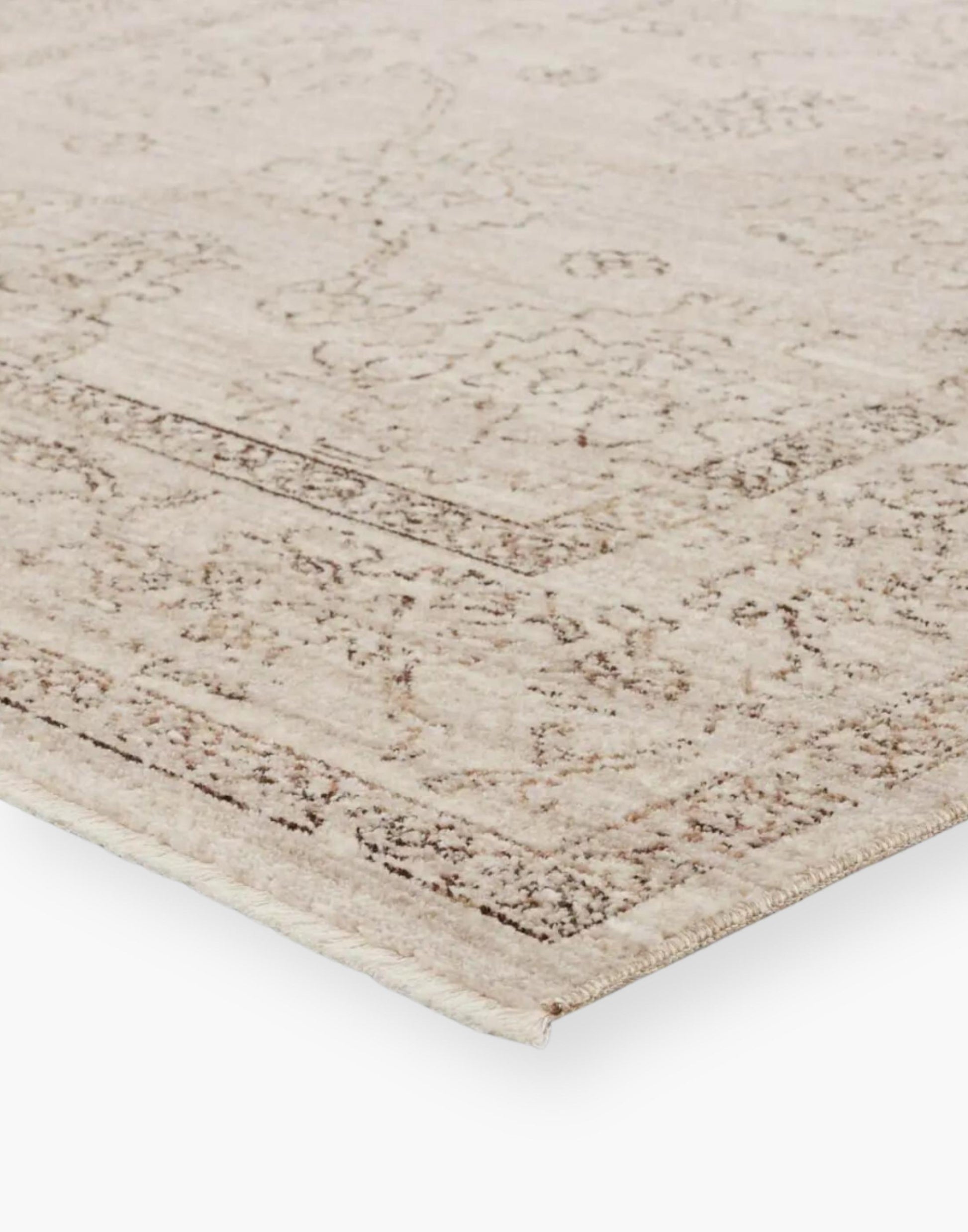 Polyester area rug that features a distressed, floral design in warm tones of brown, gray, taupe, and cream.