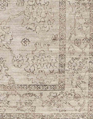 Polyester area rug that features a distressed, floral design in warm tones of brown, gray, taupe, and cream.