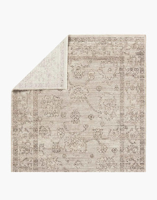 Polyester area rug that features a distressed, floral design in warm tones of brown, gray, taupe, and cream.
