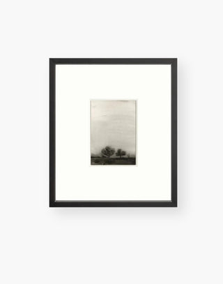 muted colors and dark tones softly blended with the grey sky portray a moody landscape and a black frame