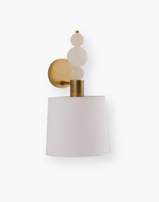 Single light sconce features three white spheres stacked on an etched cylinder that present a white linen shade with an oval antique brass iron backplate.