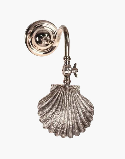 brass picture light with adjustable arm and sculptural shell detail illuminating wall artwork