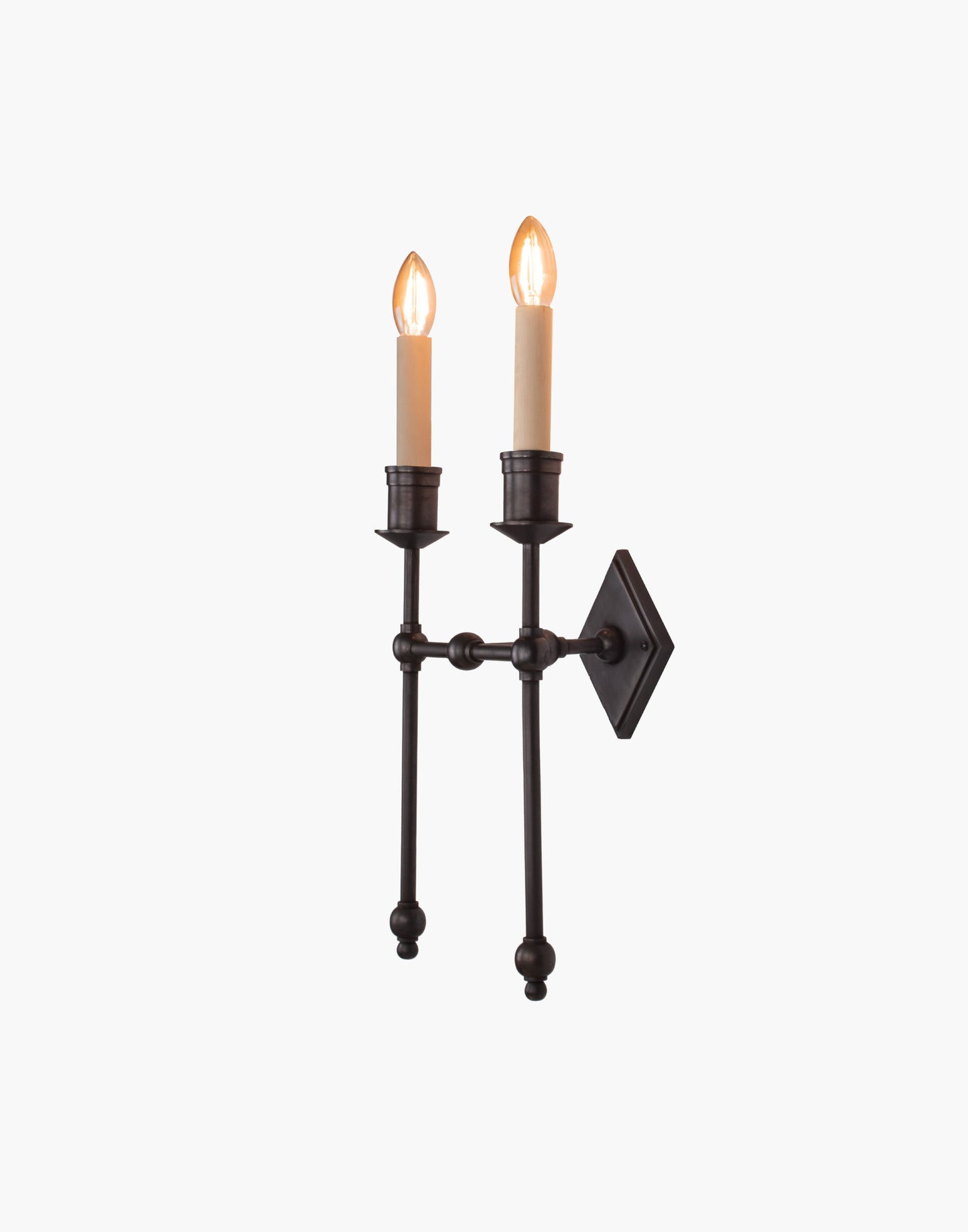 Wall sconce in cast and machined brass with diamond-shaped scalloped backplate and twin candle arms.