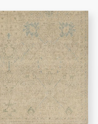 Wool rug with a distressed, floral Oushak pattern in hues of tan, blue, taupe, cream, and gray