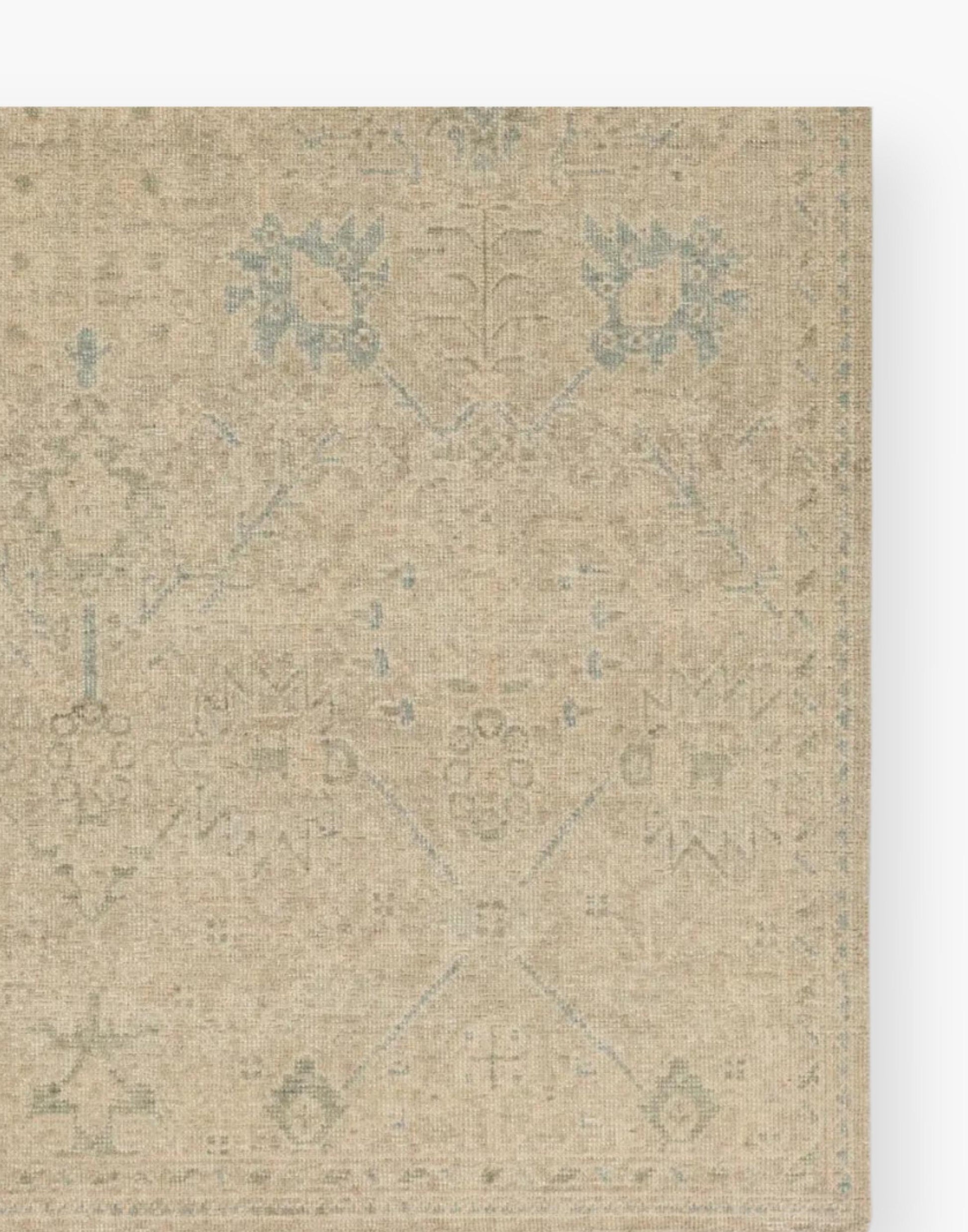 Wool rug with a distressed, floral Oushak pattern in hues of tan, blue, taupe, cream, and gray