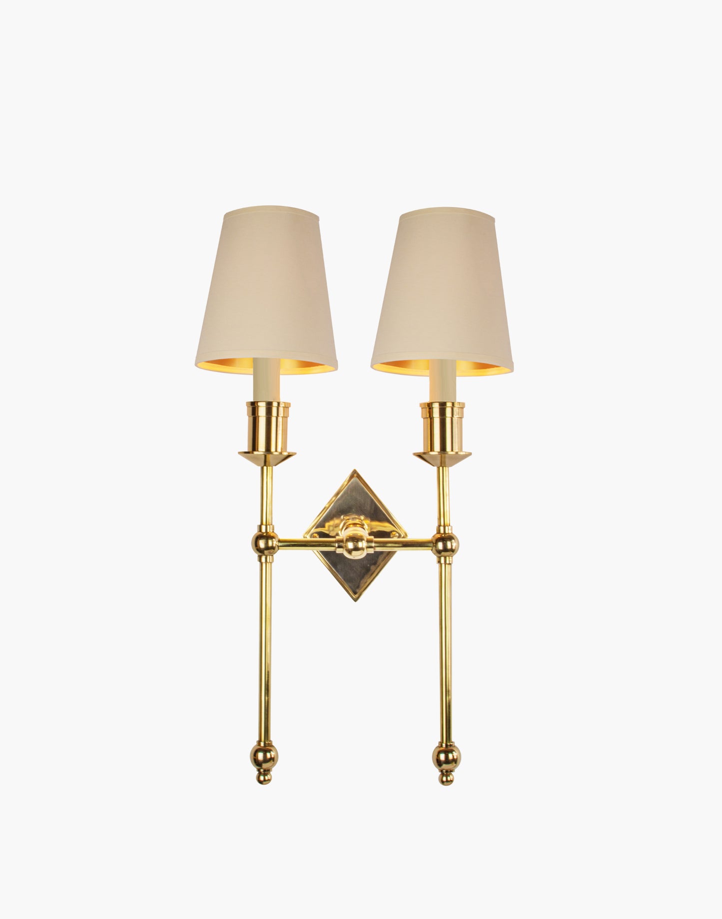 Wall sconce in cast and machined brass with diamond-shaped scalloped backplate and twin candle arms.