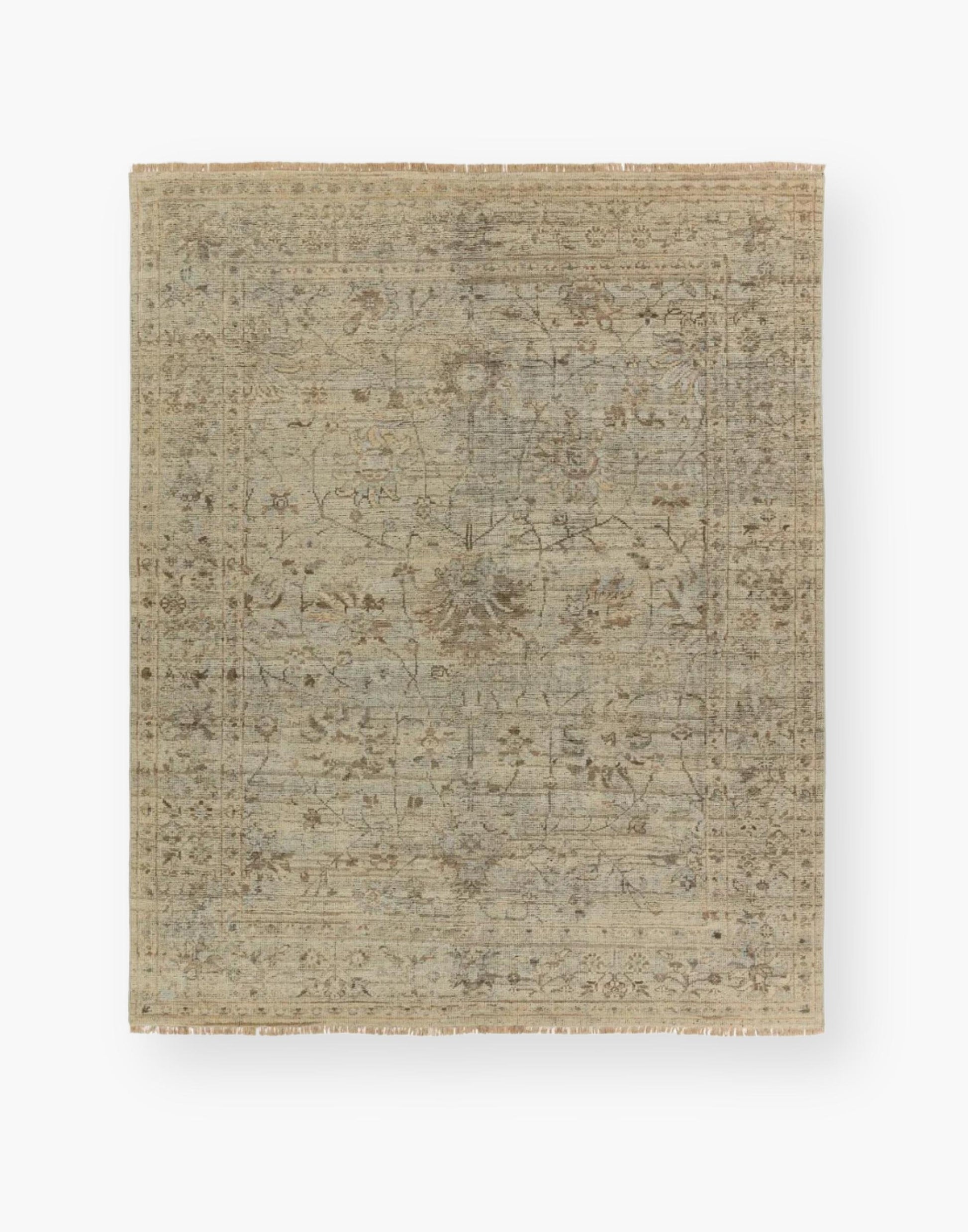Wool area rug with a washed floral motif, decorative border, and green tones accented with tan and gray hues.