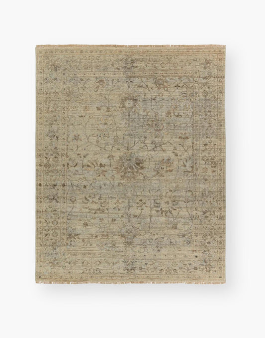 Wool area rug with a washed floral motif, decorative border, and green tones accented with tan and gray hues.