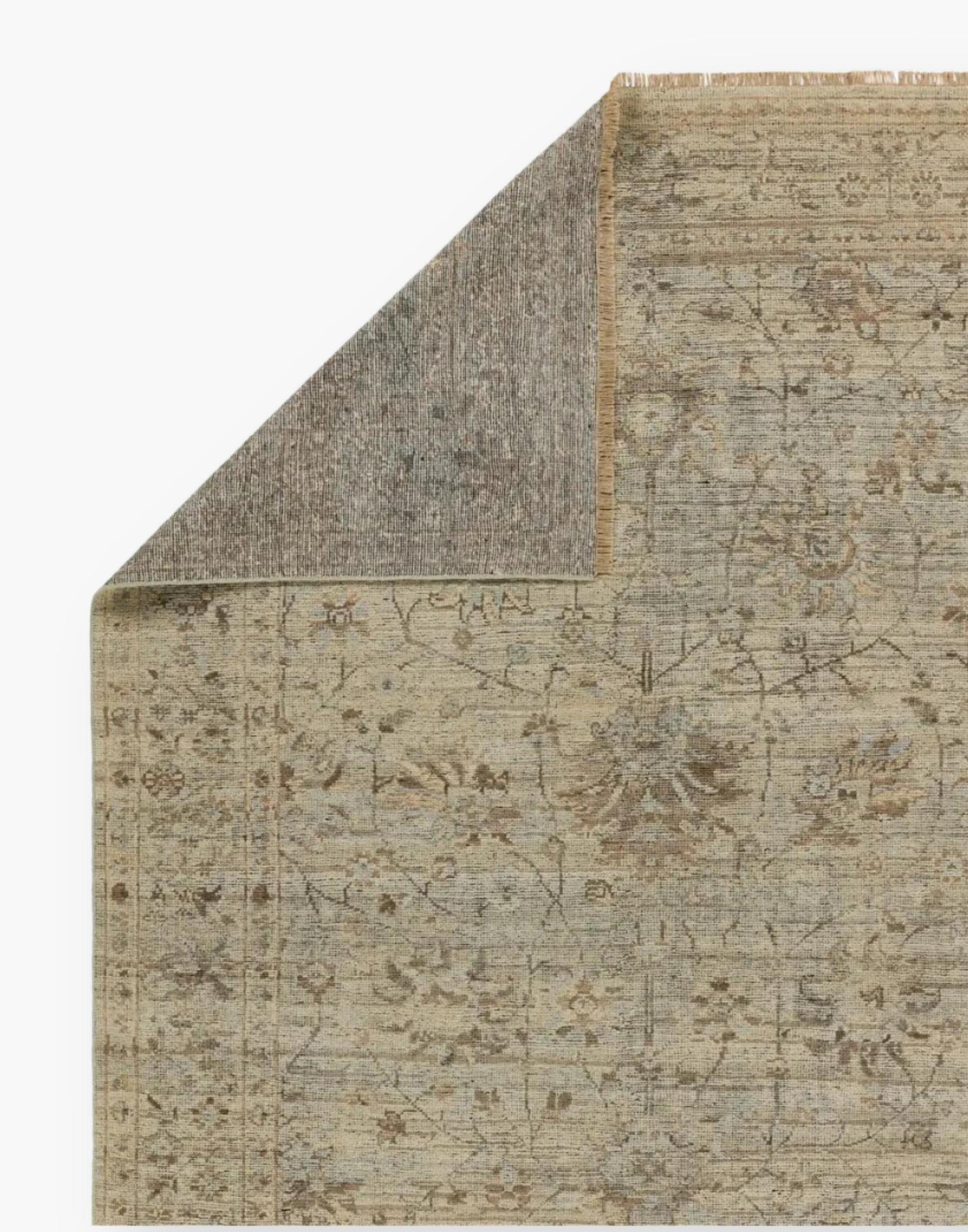Wool area rug with a washed floral motif, decorative border, and green tones accented with tan and gray hues.