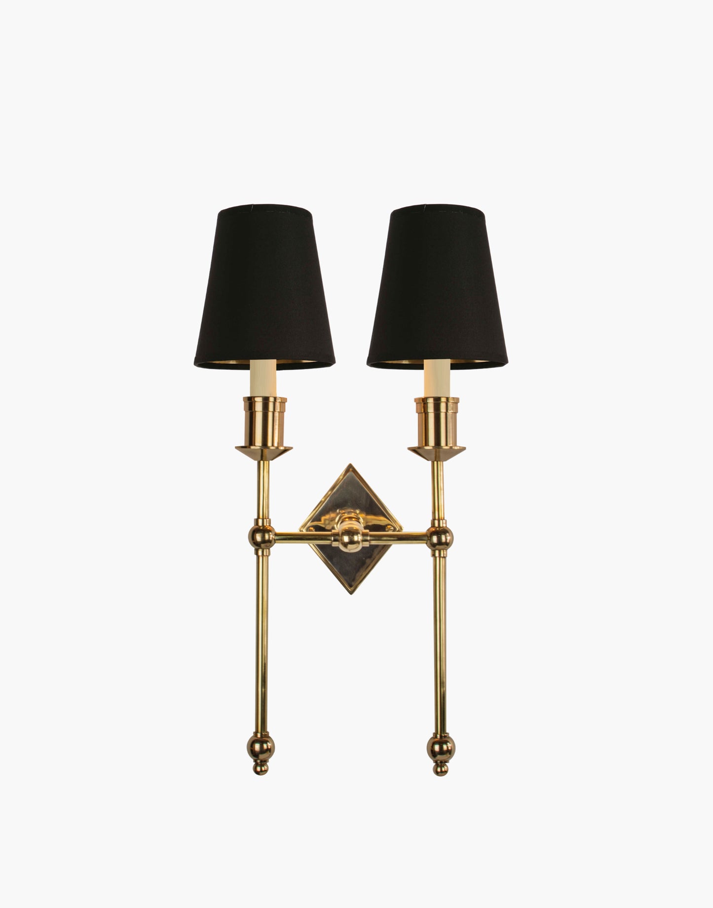 Wall sconce in cast and machined brass with diamond-shaped scalloped backplate and twin candle arms.