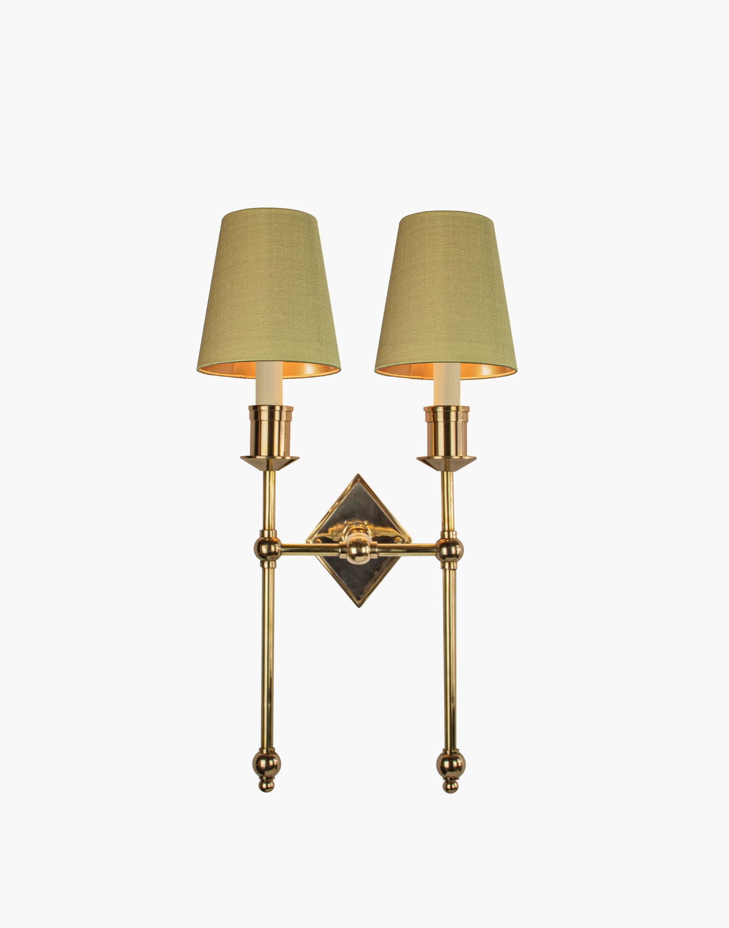 Wall sconce in cast and machined brass with diamond-shaped scalloped backplate and twin candle arms.