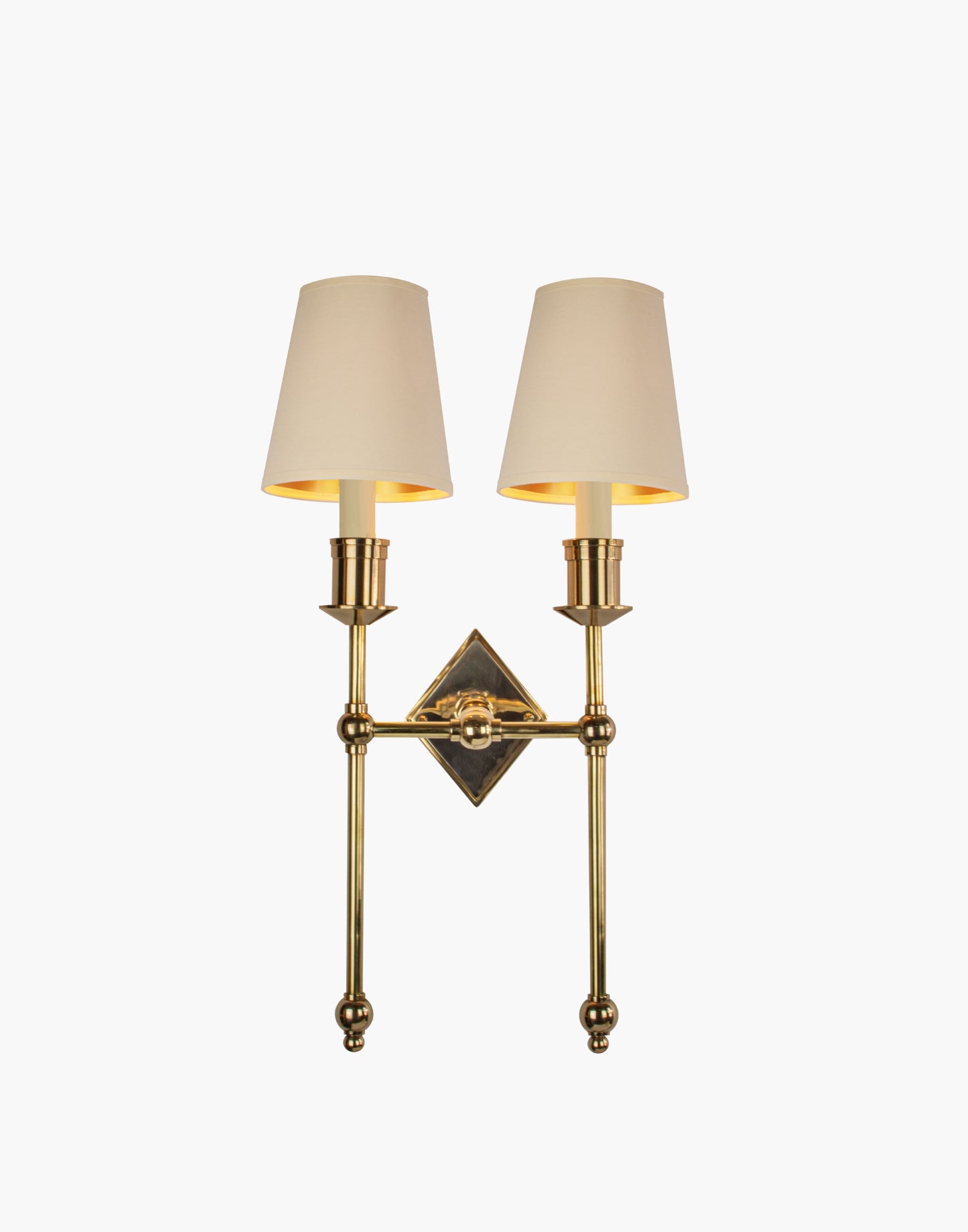 Wall sconce in cast and machined brass with diamond-shaped scalloped backplate and twin candle arms.